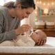 Parent applying saline nasal drops to a calm infant to relieve stuffy nose