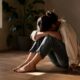 Person sitting quietly on a floor in soft light, reflecting the internal weight of complex trauma versus single-incident PTSD