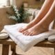 Bare feet resting after a foot soak with pumice stone and foot cream nearby