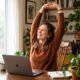 Woman stretching at her home desk during a work break to stay healthy while working from home