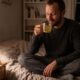 Man holding a warm mug of passionflower tea in bed at night before sleep